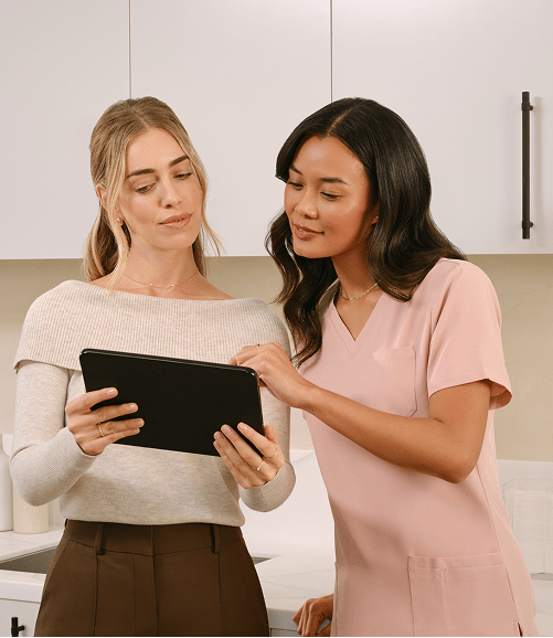 Two women reviewing a tablet together in a bright kitchen setting