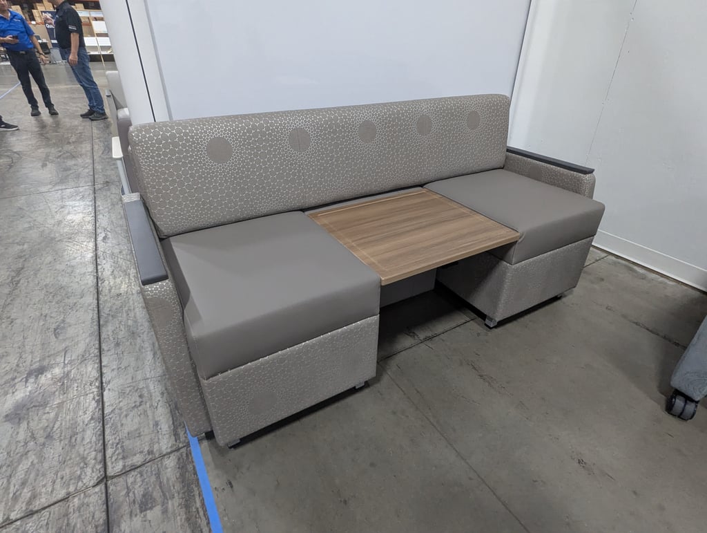 Grey upholstered booth seating with a patterned backrest and a central wooden tabletop
