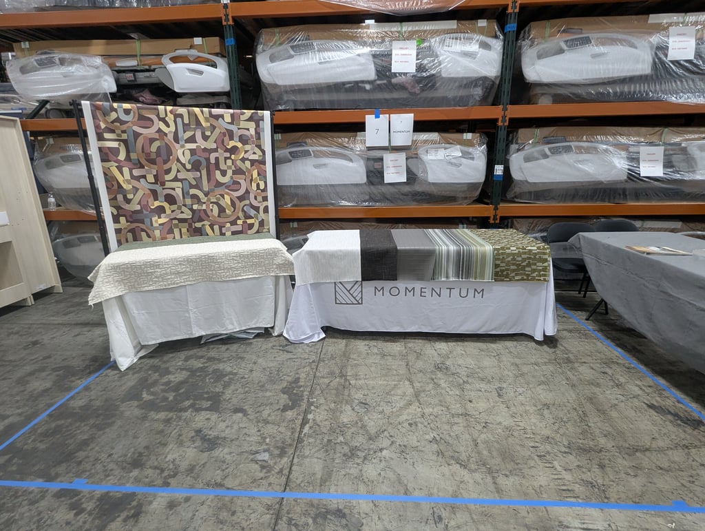 Fabric swatches and a patterned headboard on the Momentum display tables at booth 7