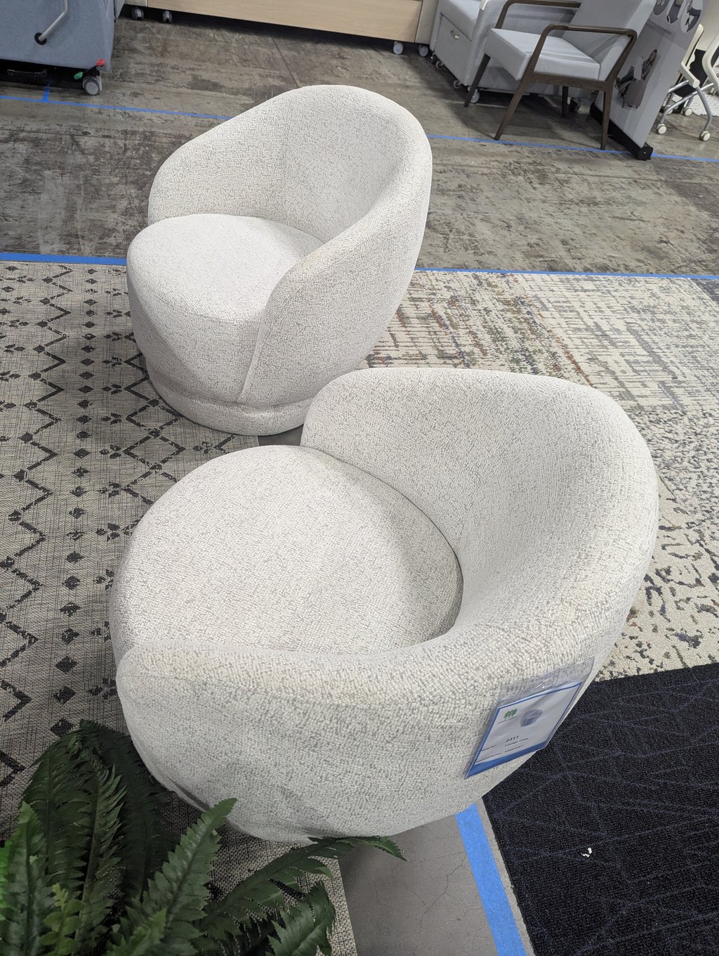 Two rounded light grey lounge chairs displayed on patterned rugs