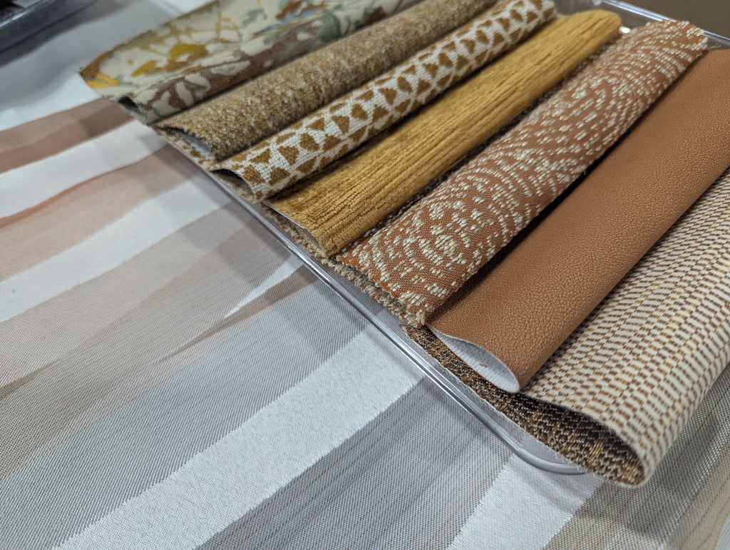 Rolled fabric samples fanned out in beige, mustard and terracotta weaves and textures