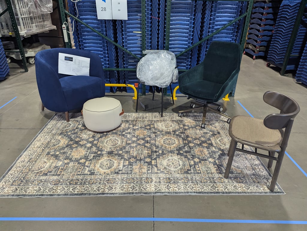 A blue armchair, a round ottoman and a green swivel chair on a patterned rug at the JSI booth, number 28