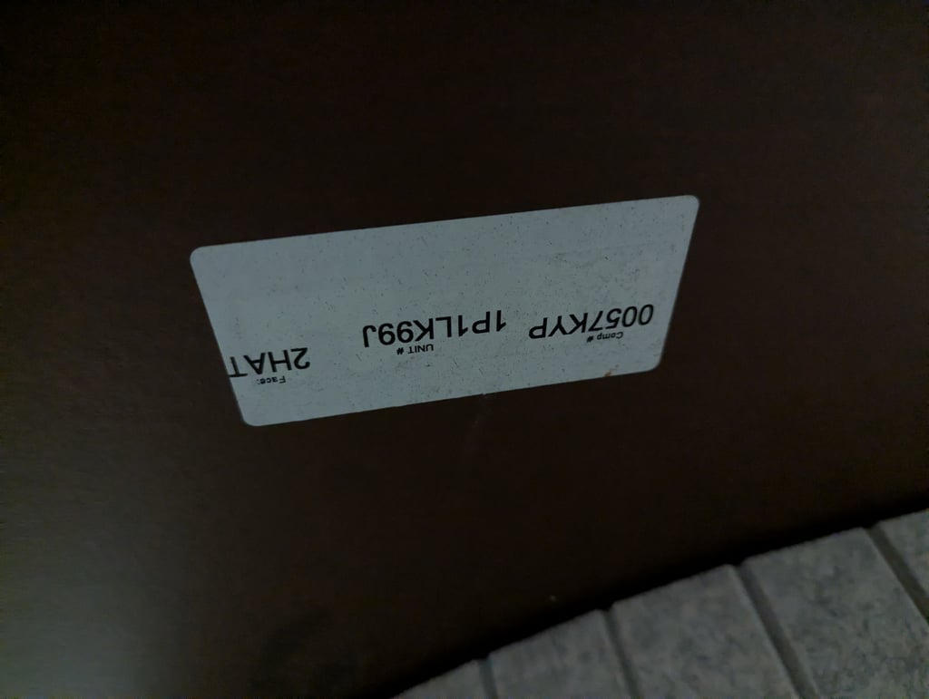 A close view of a white unit number label on a dark brown furniture surface