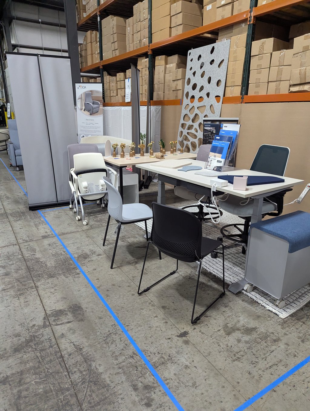 Desks, chairs and partition panels in front of the IOA Recliners banner
