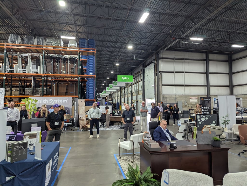 A wide view of the event floor with attendees gathered among the booth displays and shelving