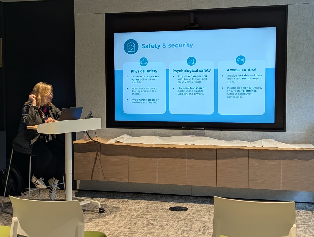 A presenter at a podium beside a screen showing a Safety and security slide with three panels