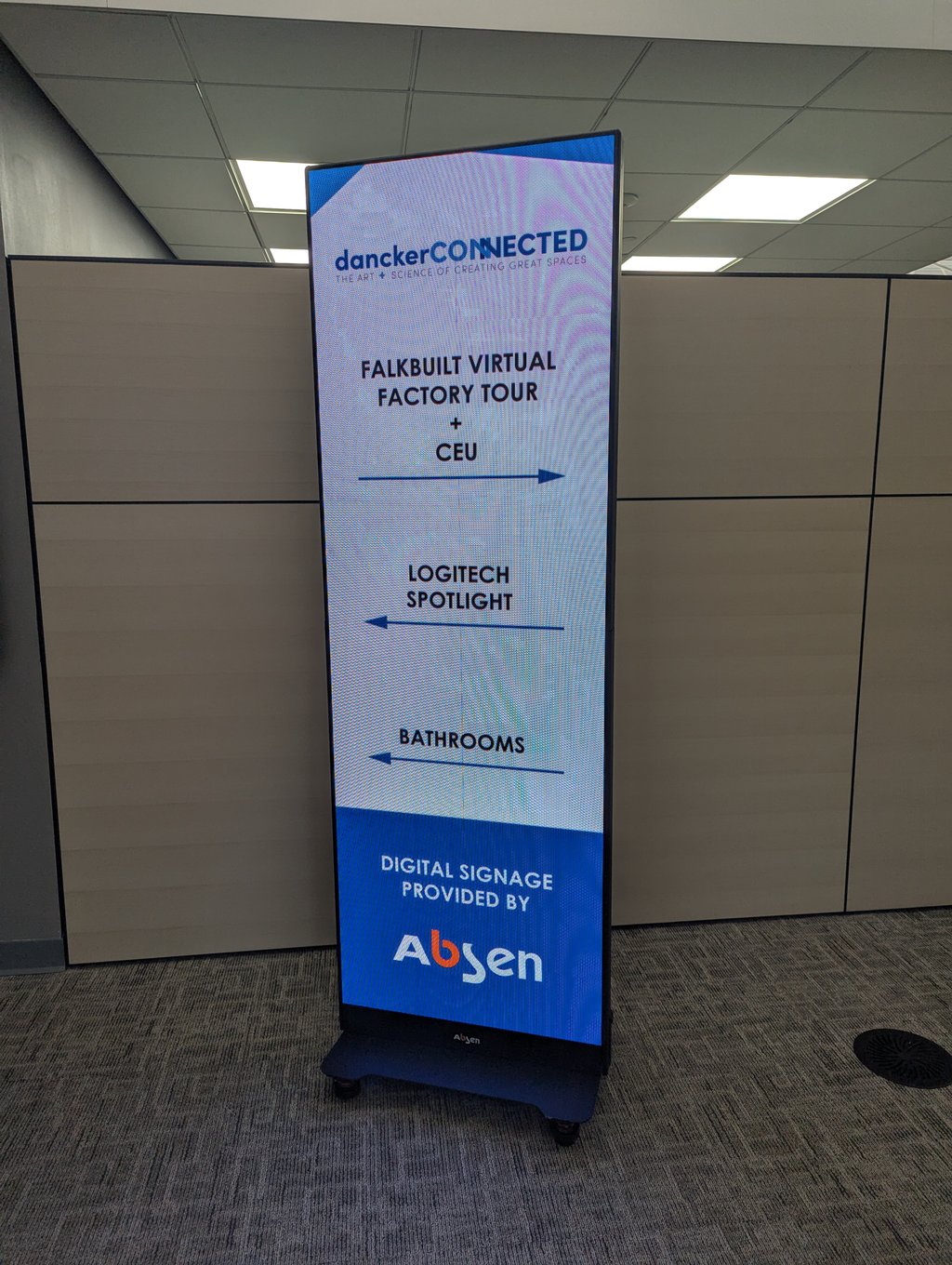Digital signage in the lobby directing attendees to the Falkbuilt virtual factory tour and CEU session
