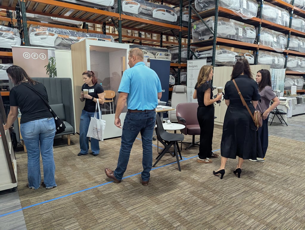 Attendees browsing furniture displays at the OFS stand with wrapped mattresses on the racking behind