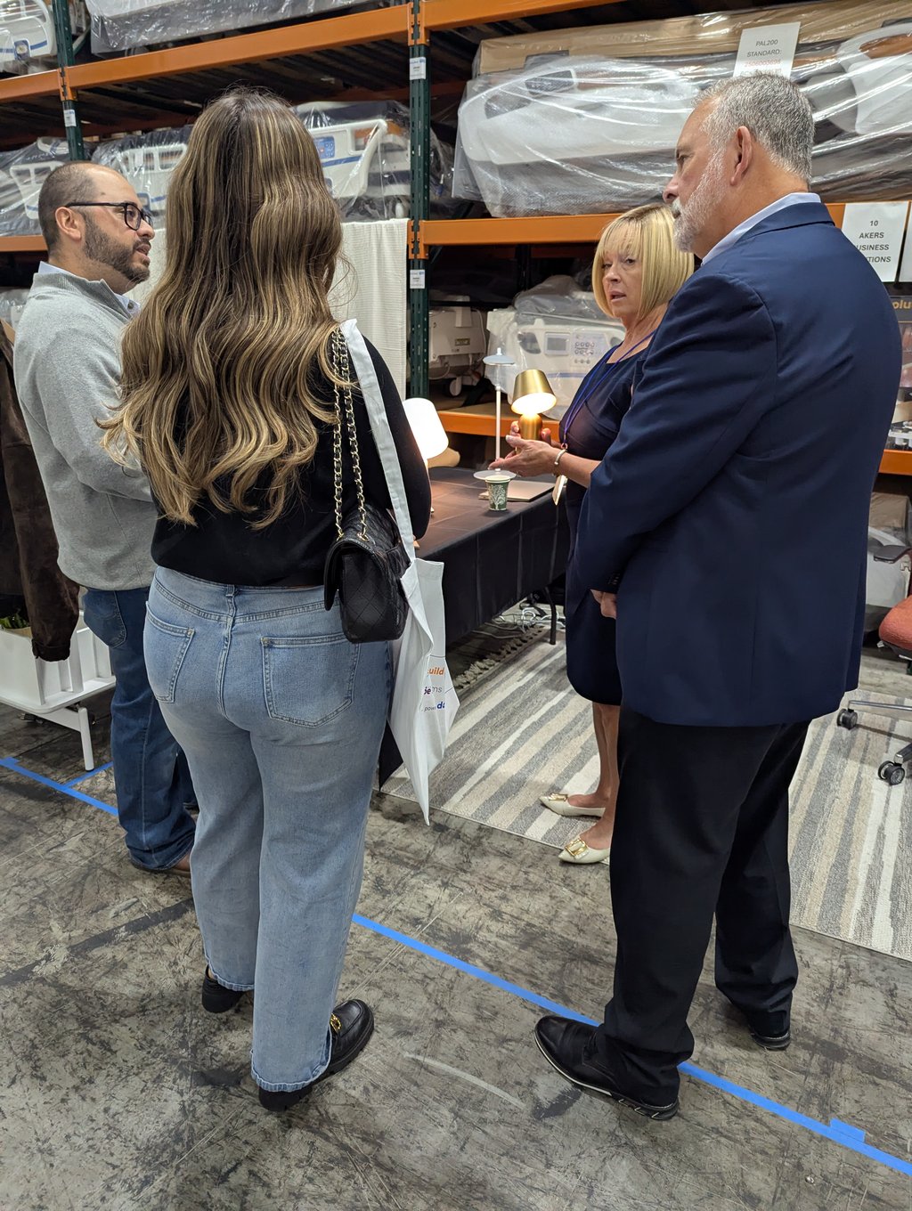 Four attendees talking around a table of small lit lamps at the Akers Business booth, number 10