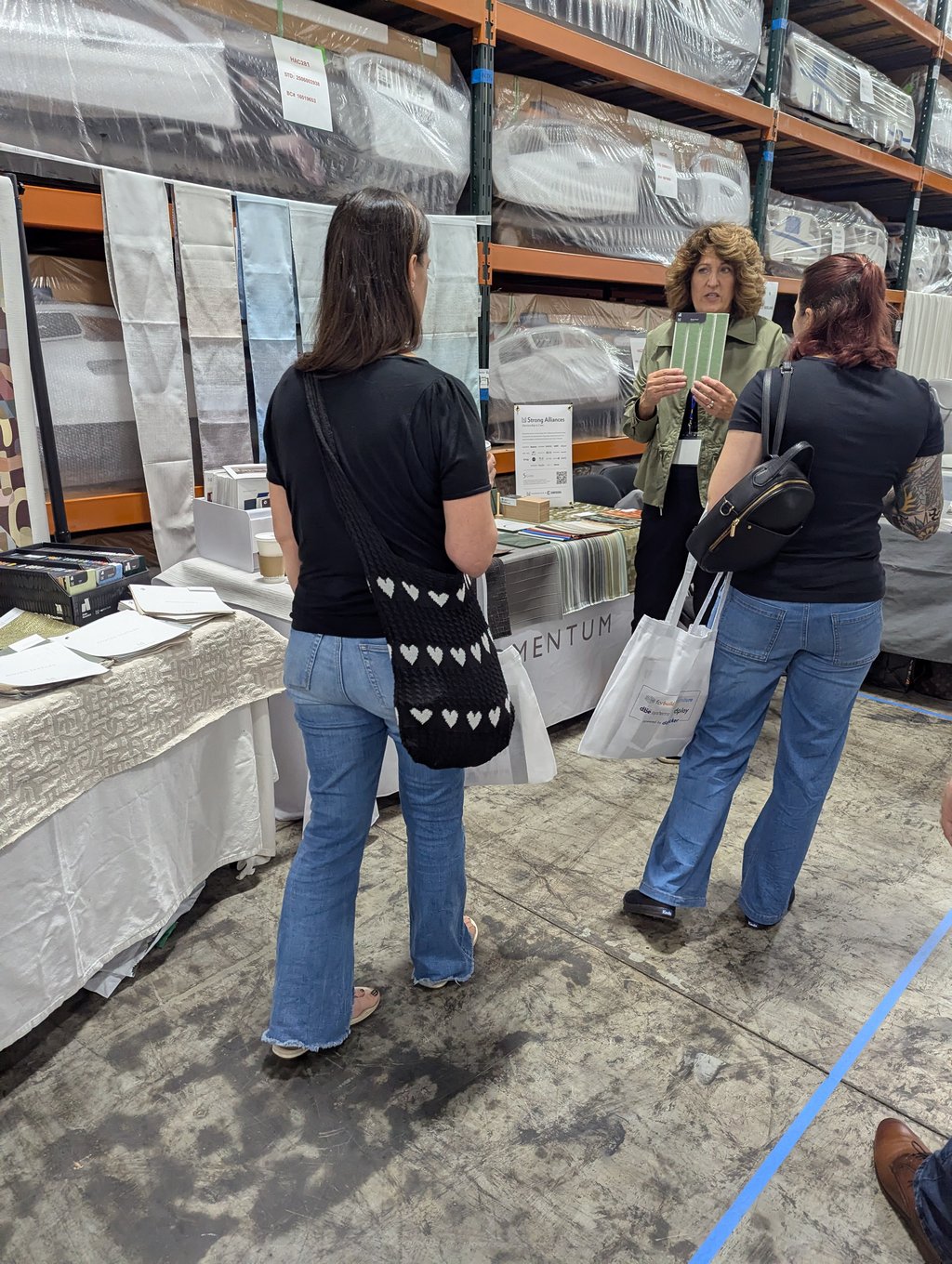 An exhibitor holding up a green fabric sample for two visitors at the Momentum stand