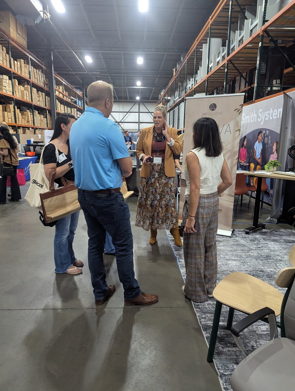 Four attendees in conversation between the Hat Collective and Smith System banners