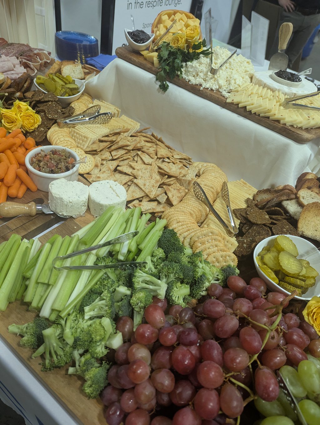 Grapes, crudites, crackers, cheeses and meats on the grazing board beside a respite lounge sign