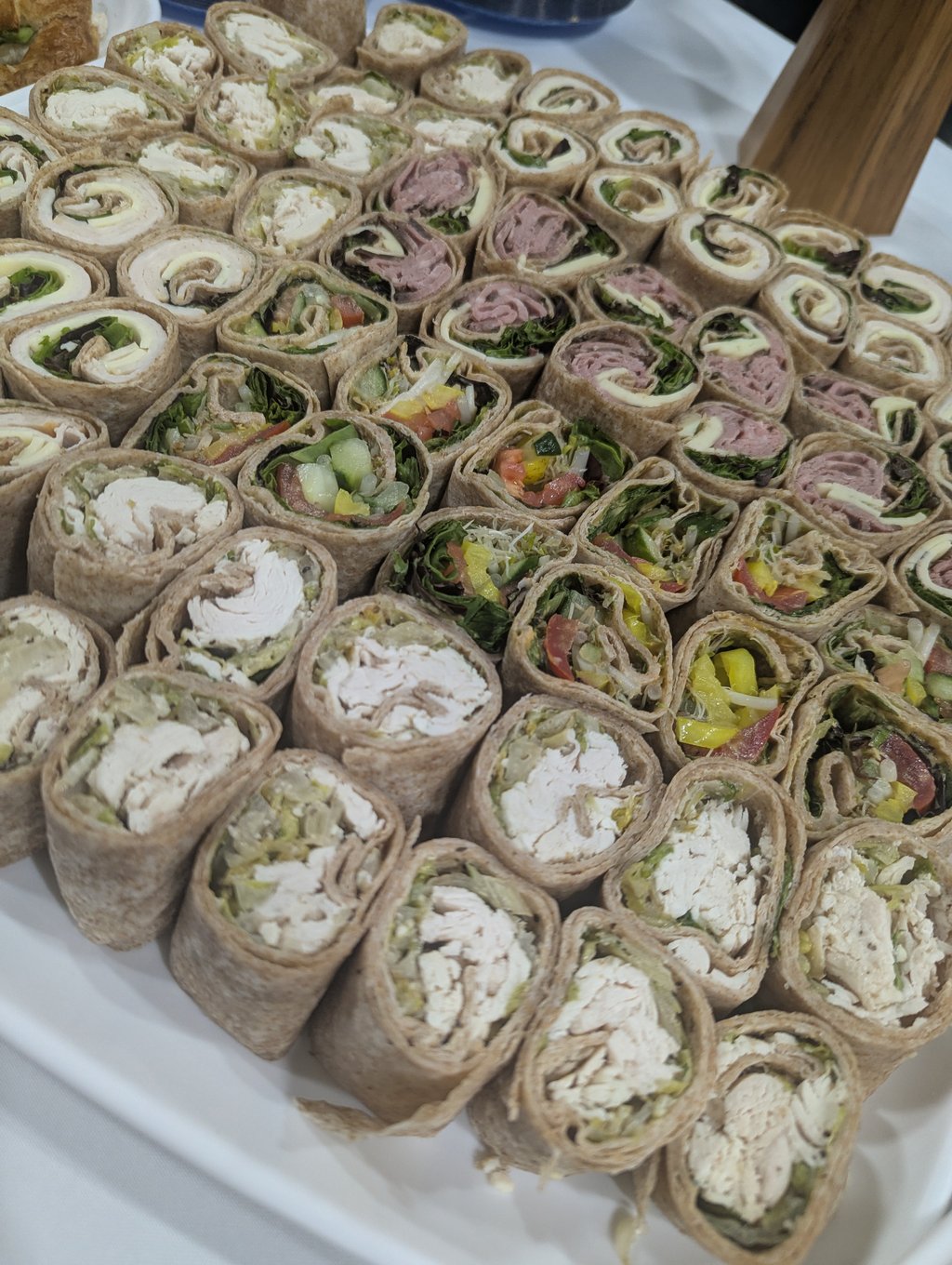 A close view of rolled tortilla wraps cut into pinwheel slices filled with meat, cheese and salad