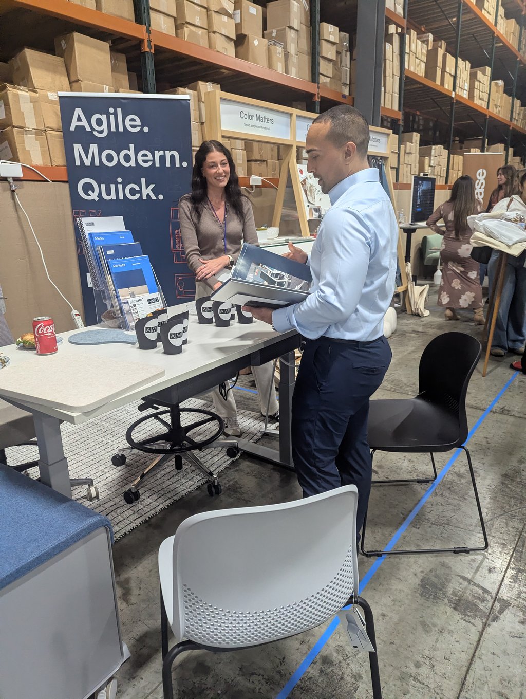An attendee leafing through a catalogue at a counter beside the Agile Modern Quick banner