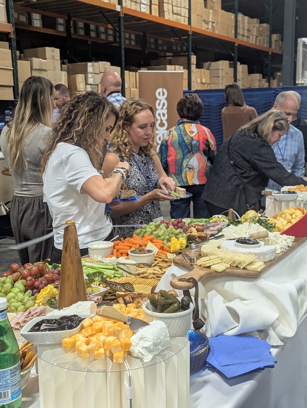 Attendees helping themselves to cheeses, crackers, grapes and crudites below the Steelcase banner