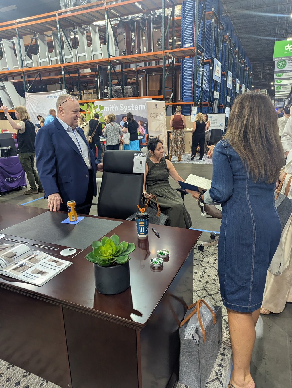 Attendees gathered around a dark wood desk and office chair beneath the Smith System banner and Corva sign