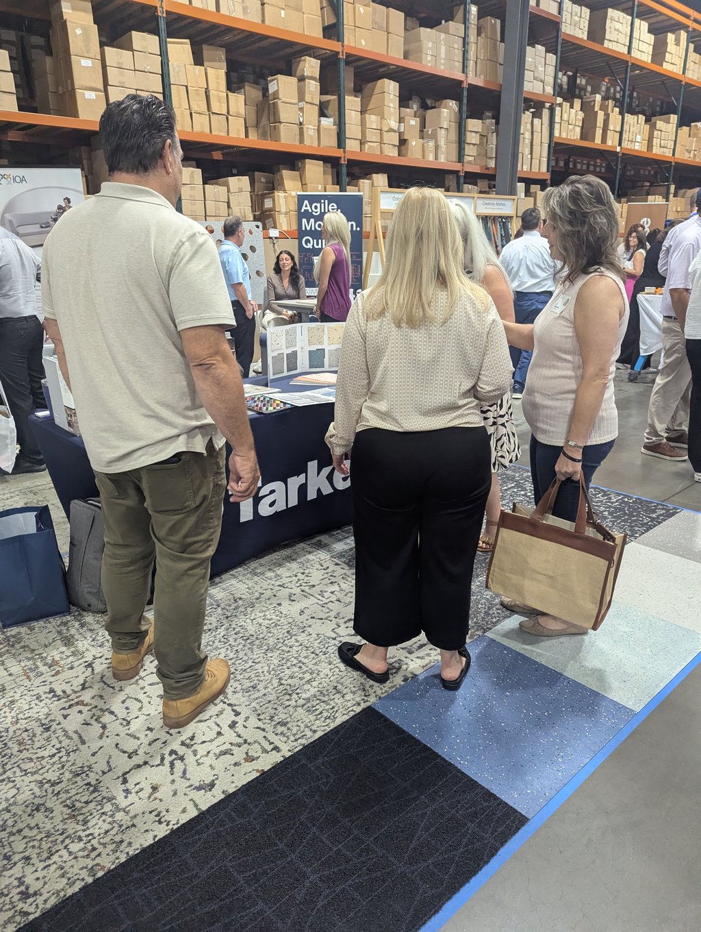 A group of attendees around a booth table beneath the Agile banner in the warehouse