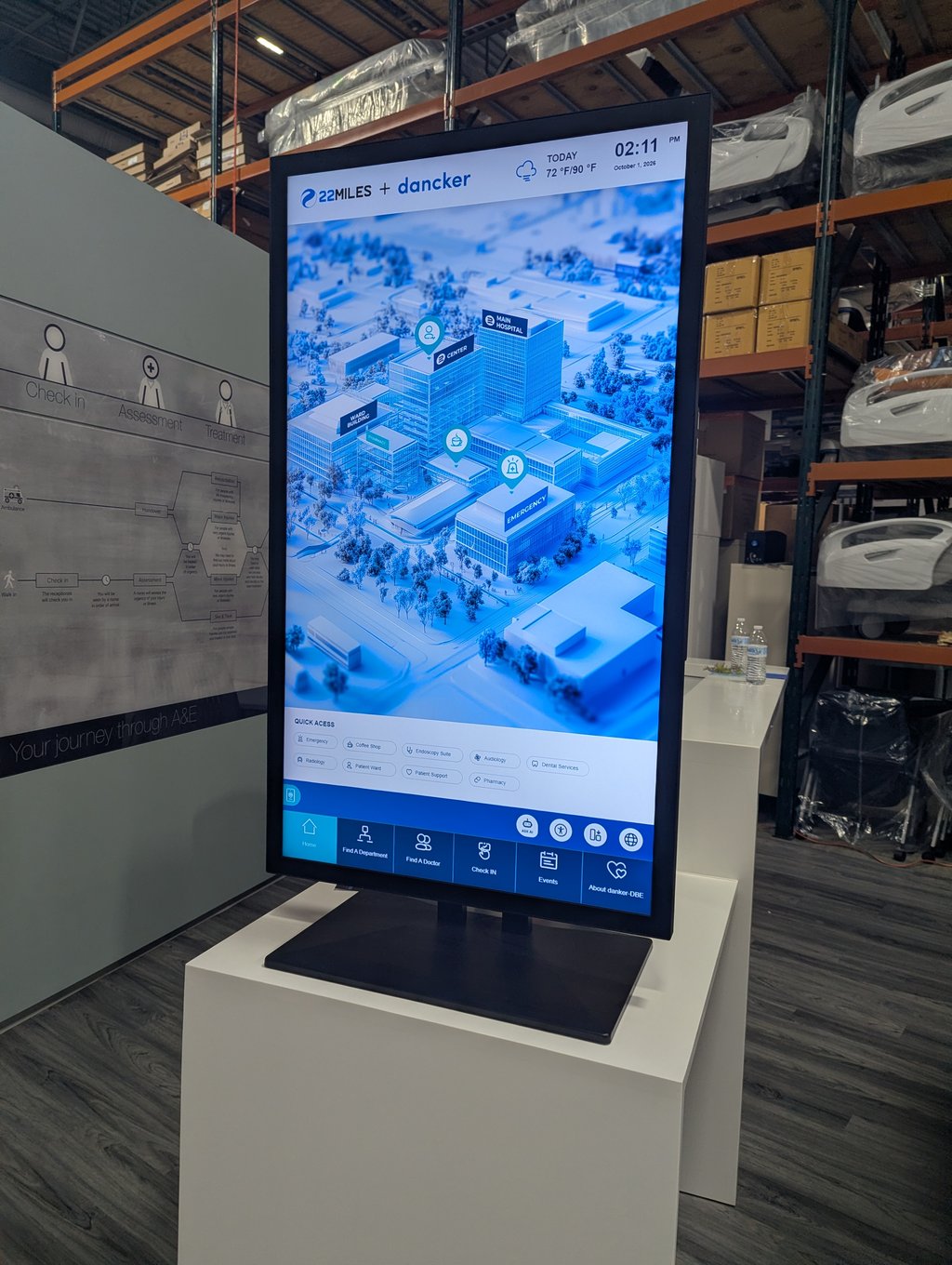 A tall touchscreen wayfinding kiosk showing a 3D hospital map with department and doctor search options