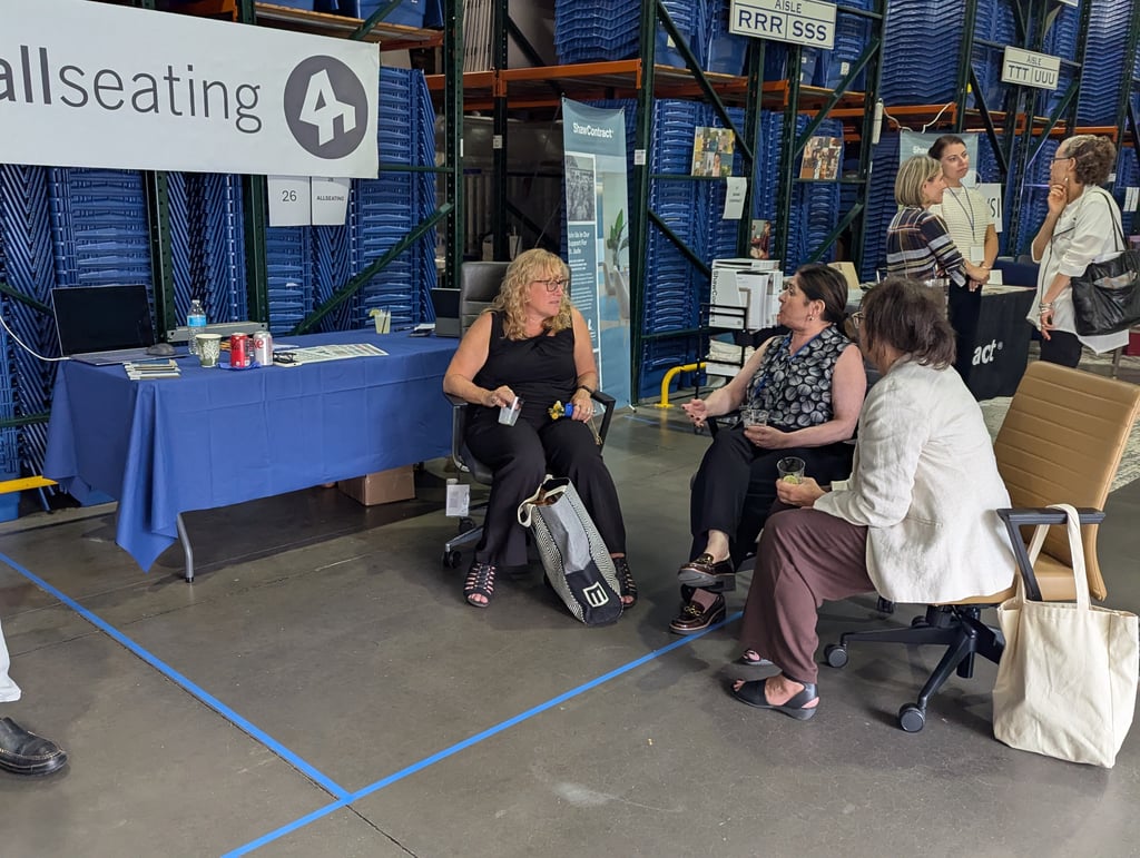 Attendees seated and talking at the Allseating booth with its blue covered table