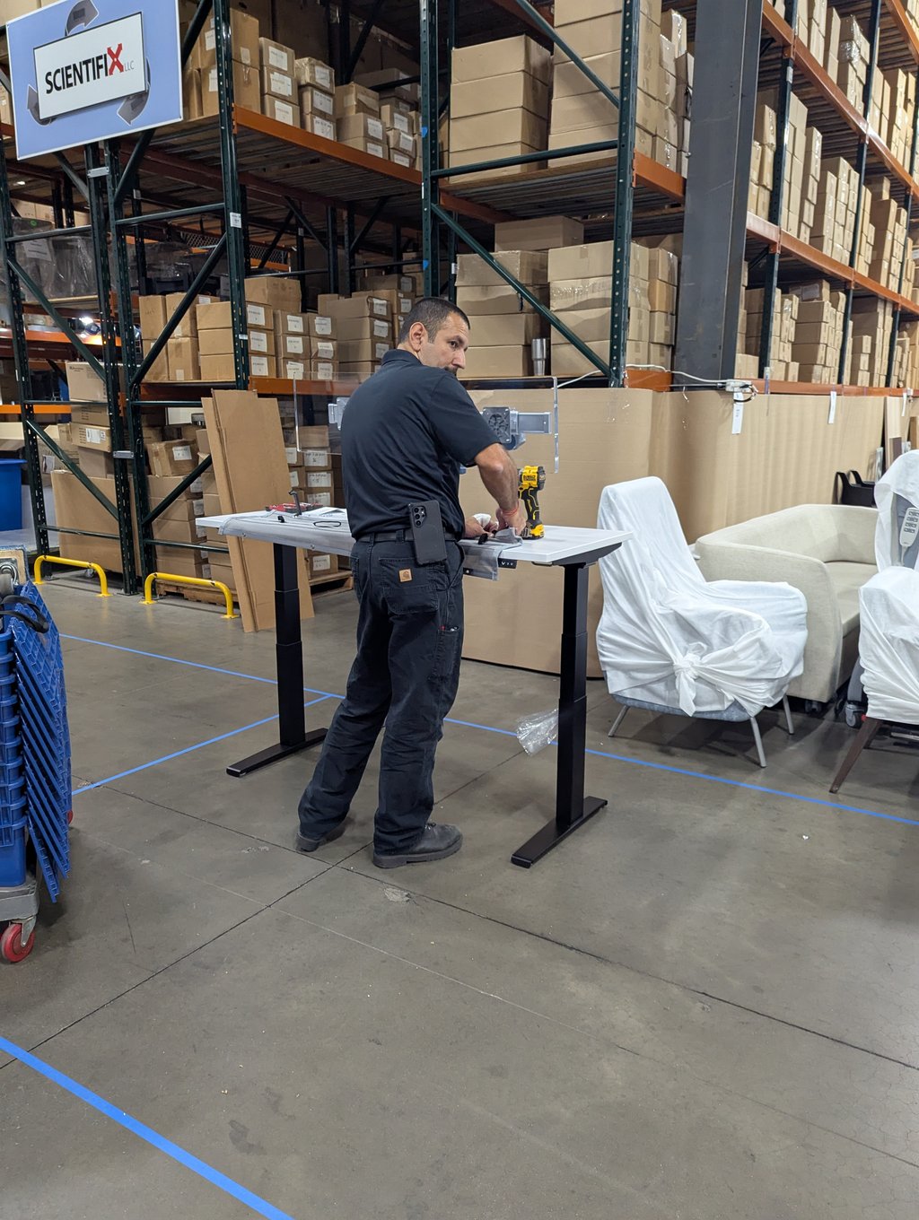 An exhibitor assembling a height-adjustable desk with a cordless drill