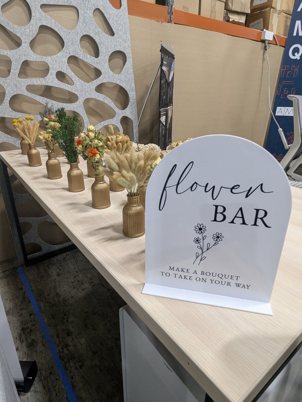 The flower bar table lined with gold vases of dried flowers for attendees to take away