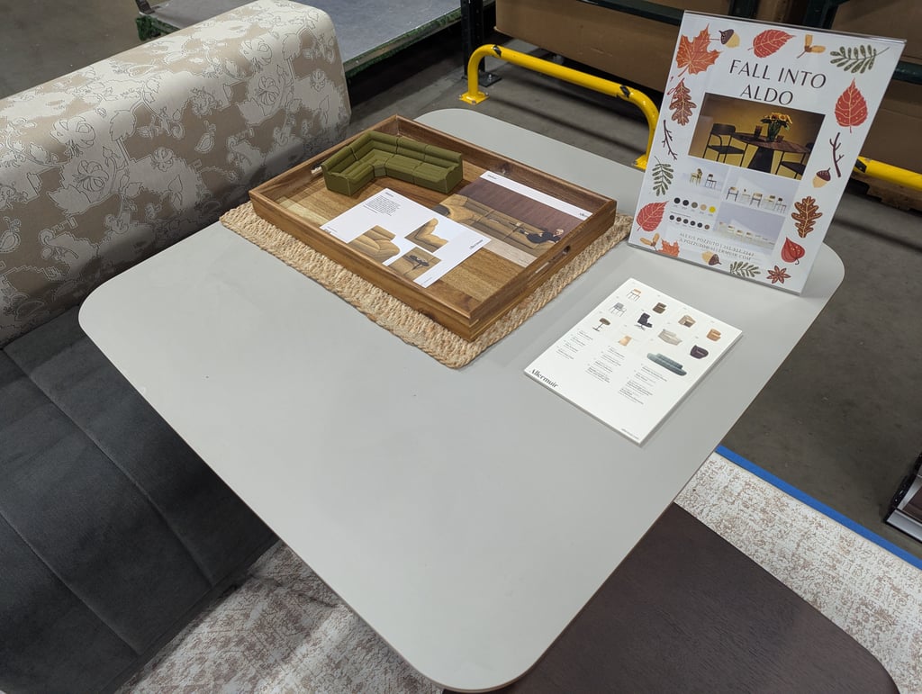 A Fall Into Aldo sign beside a sectional model and material samples on a table