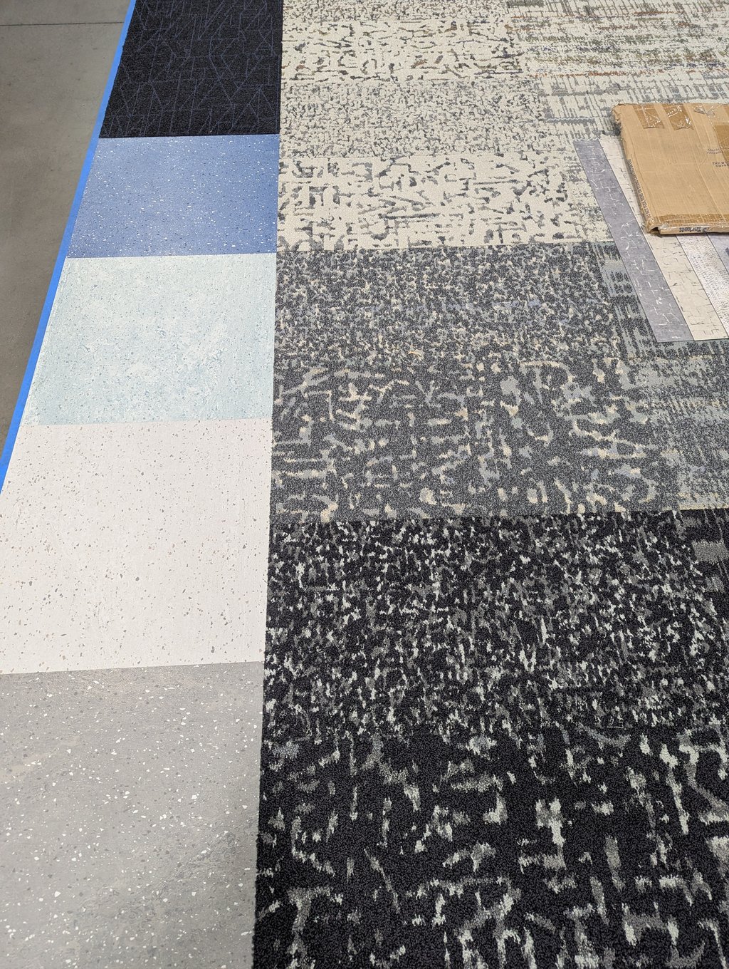 Overhead view of vinyl and patterned carpet tile samples laid out side by side