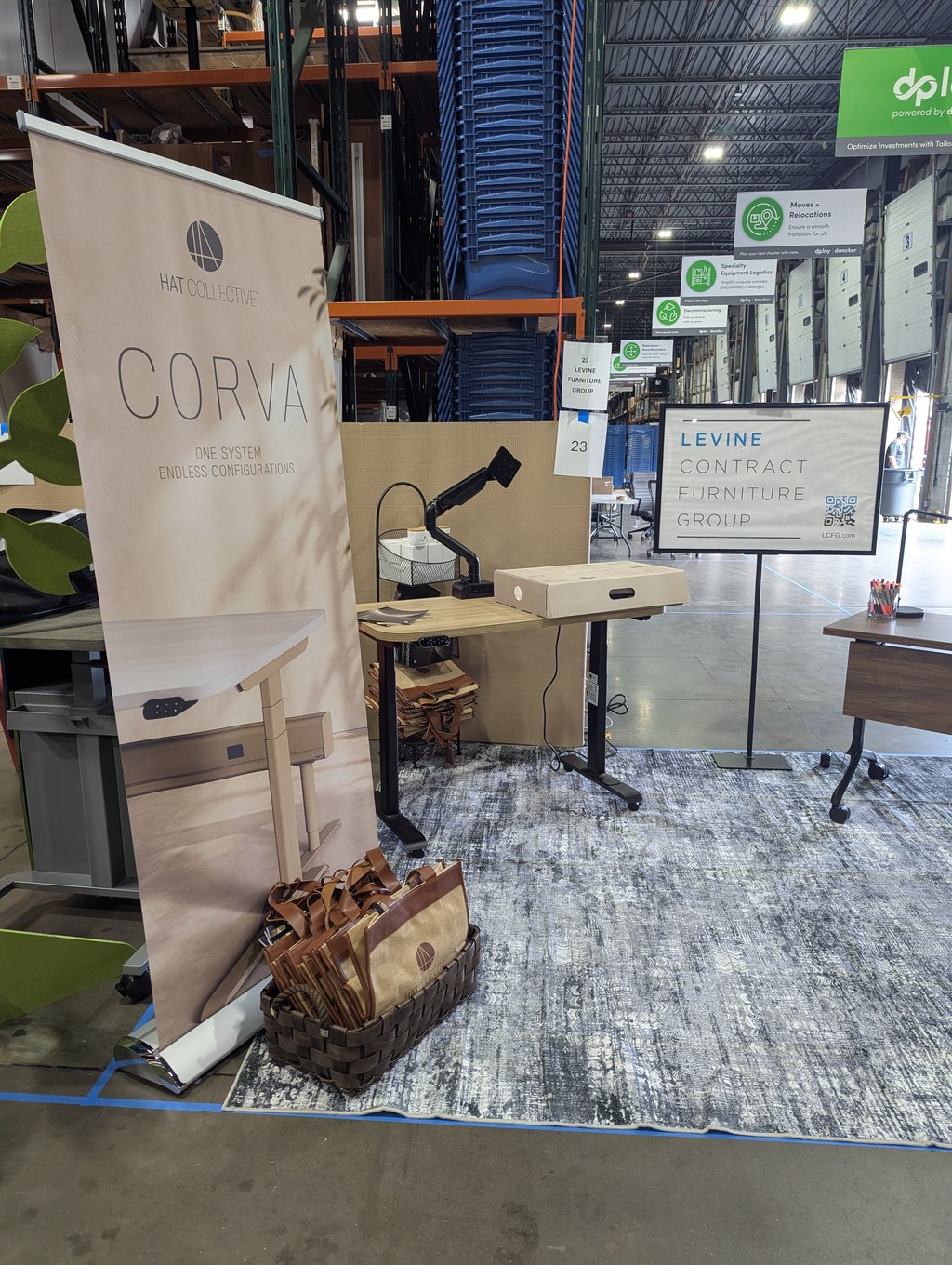 The Corva and Levine booth with a standing desk and tote bags in a basket