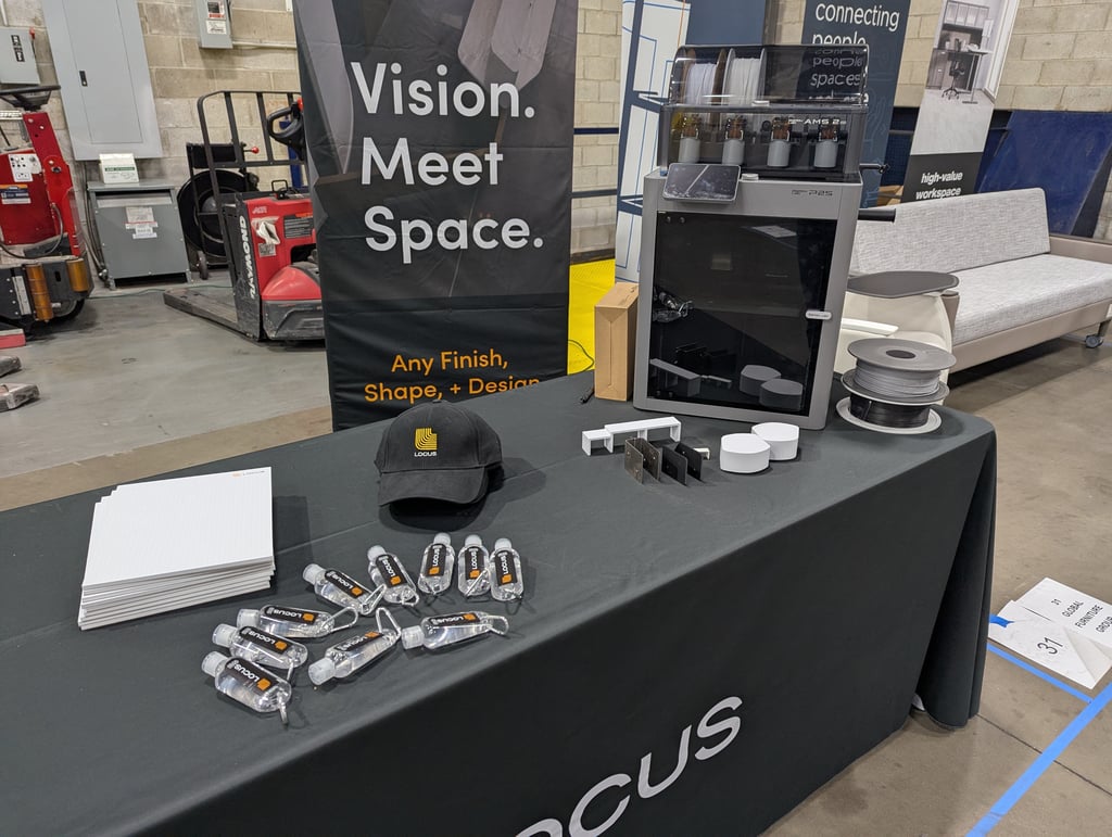 The Locus booth with a 3D printer, filament spools and a Vision Meet Space banner