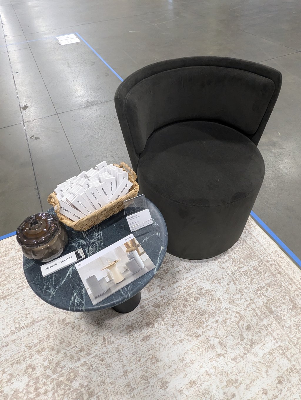 A round black Senator chair beside a marble side table of Allermuir literature