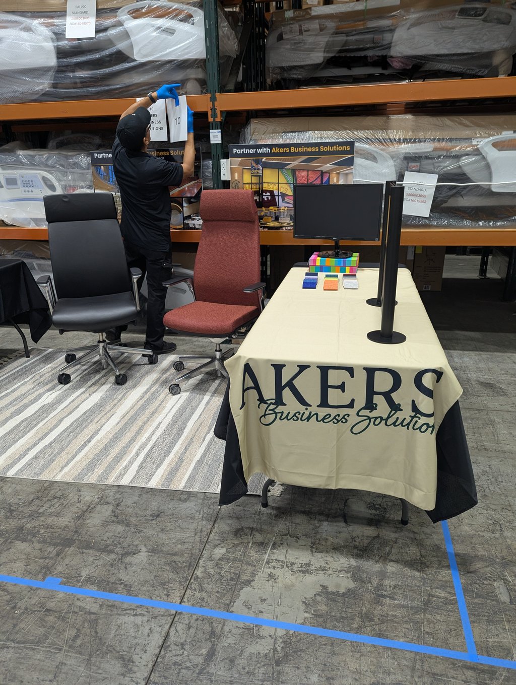 An exhibitor attaching the booth 10 number to shelving at the Akers display