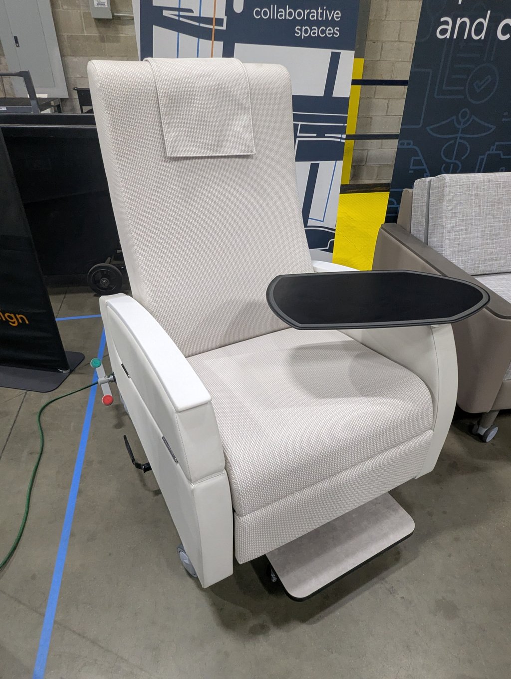 A beige recliner with a fold-out tray and wheeled footrest on display