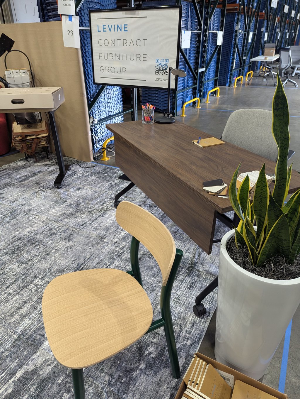 A wood desk and chair staged under the Levine Contract Furniture Group sign