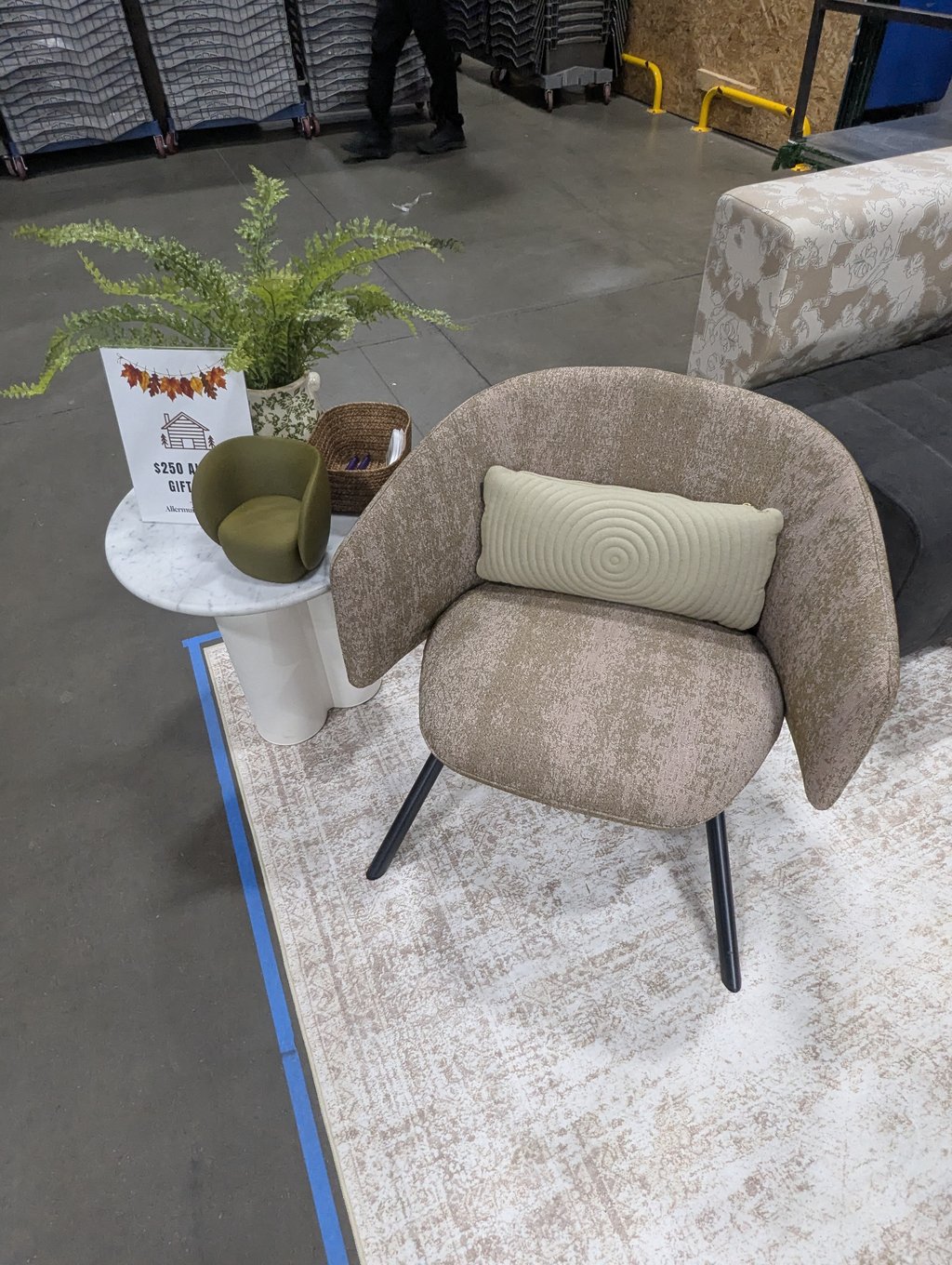 A beige lounge chair on a patterned rug beside a side table with a potted plant
