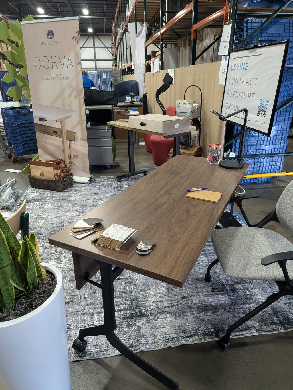 A Corva table on a rolling base with fabric swatches, pens and a lamp