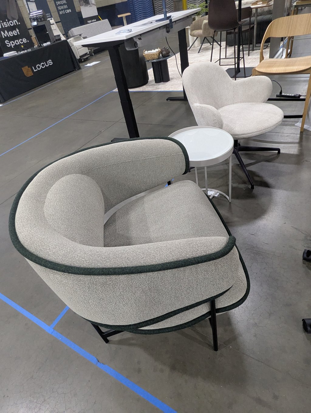 Two grey lounge chairs and a side table in front of the Locus booth fabric
