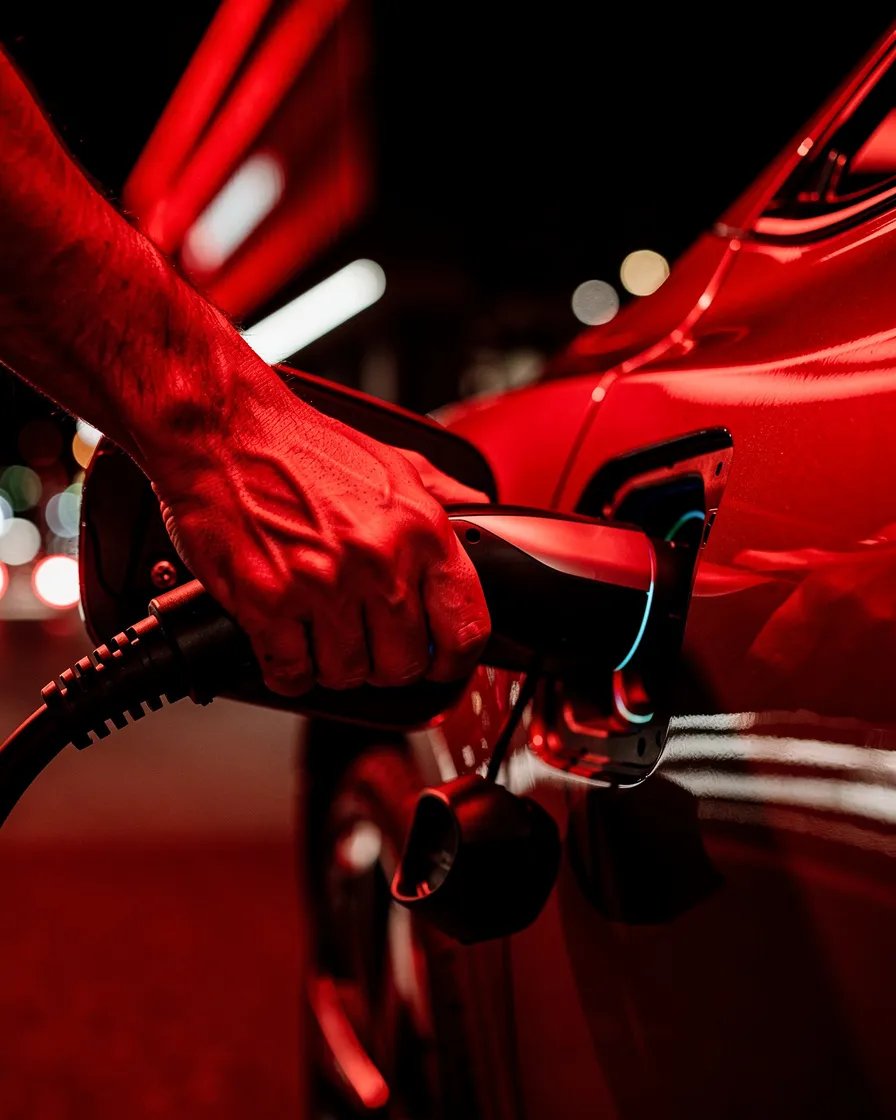 Person charging an electric vehicle with red wash