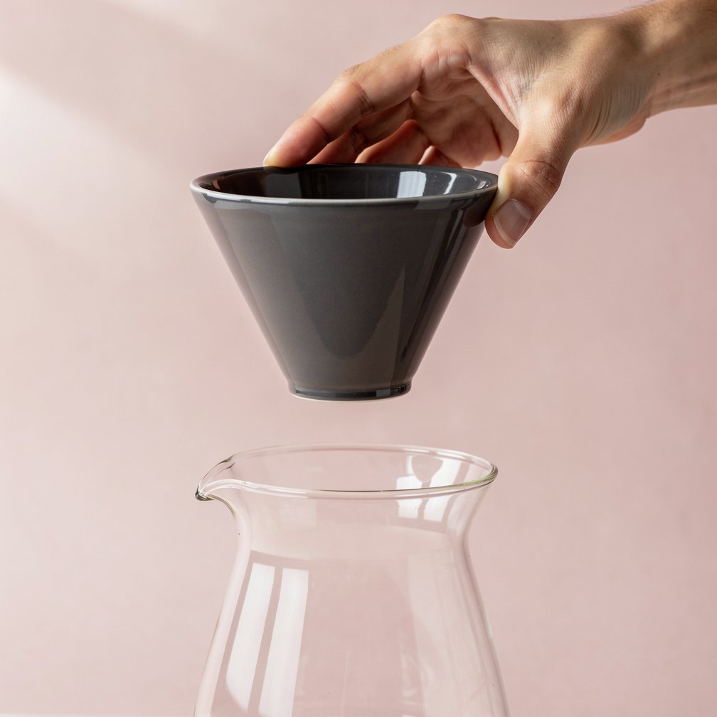 Hand holding dripper over carafe