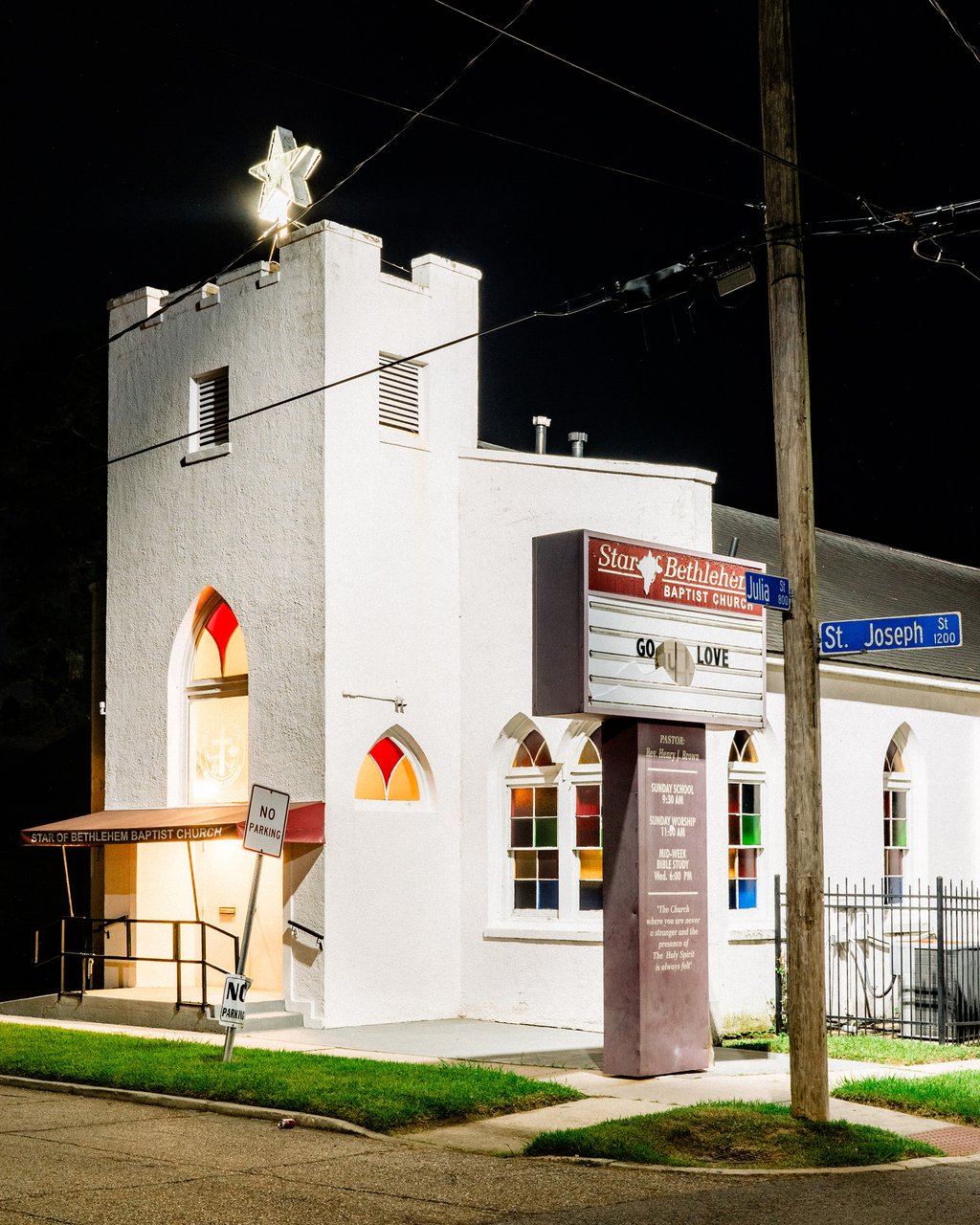 Night view of Star of Bethlehem Baptist Church with an illuminated star atop the white tower and a marquee reading GO LOVE