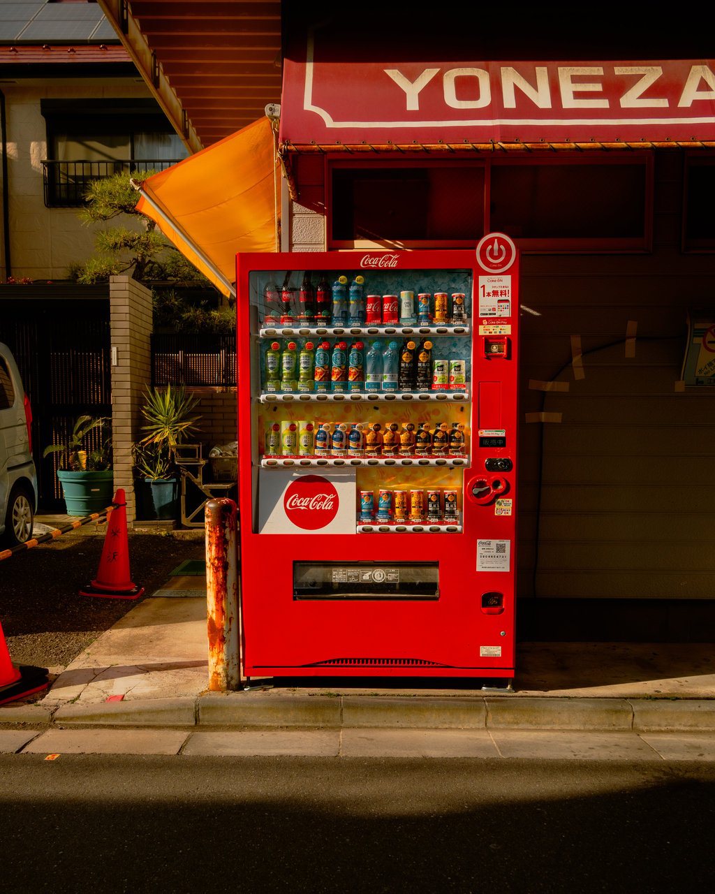 Red Coca-Cola vending machine beneath a red storefront awning