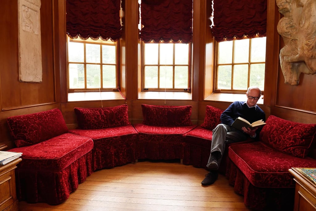 Visitor sat reading in the bay window of the Library at Lyme Park, Cheshire