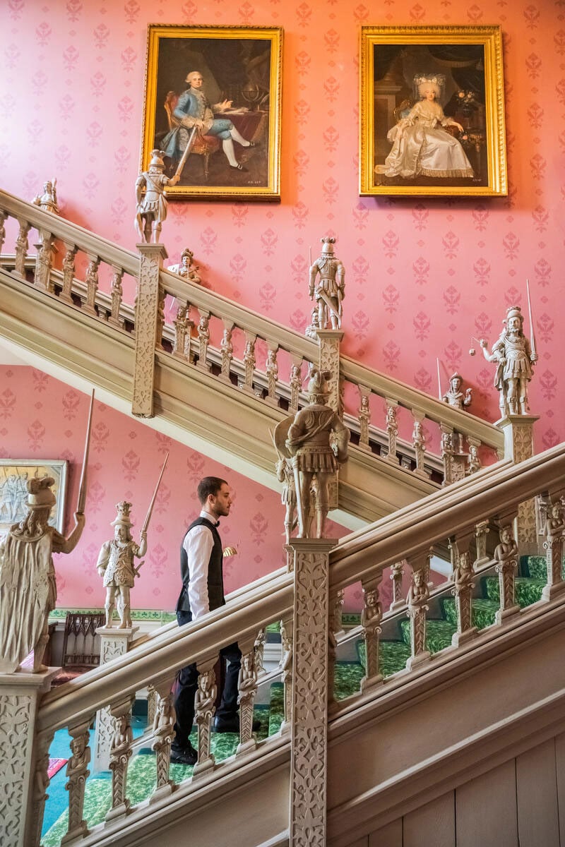 Porter carrying luggage up the staircase at Hartwell House and Spa, Buckinghamshire.