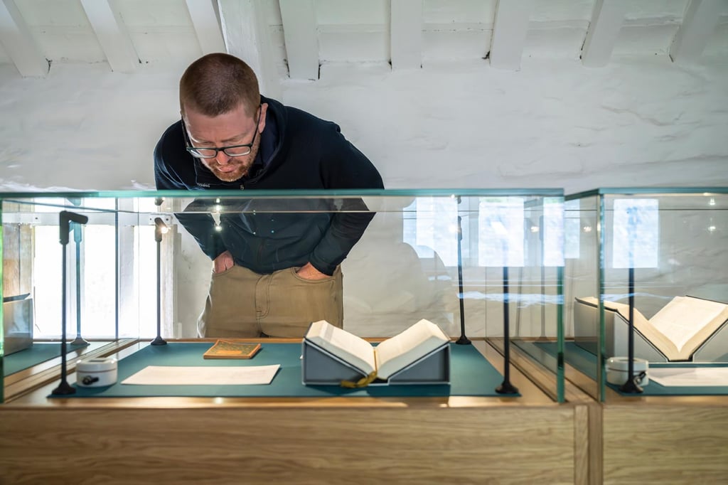 Visitor examining Bibles in different languages displayed in glass cases at Tŷ Mawr Wybrnant, Conwy.
