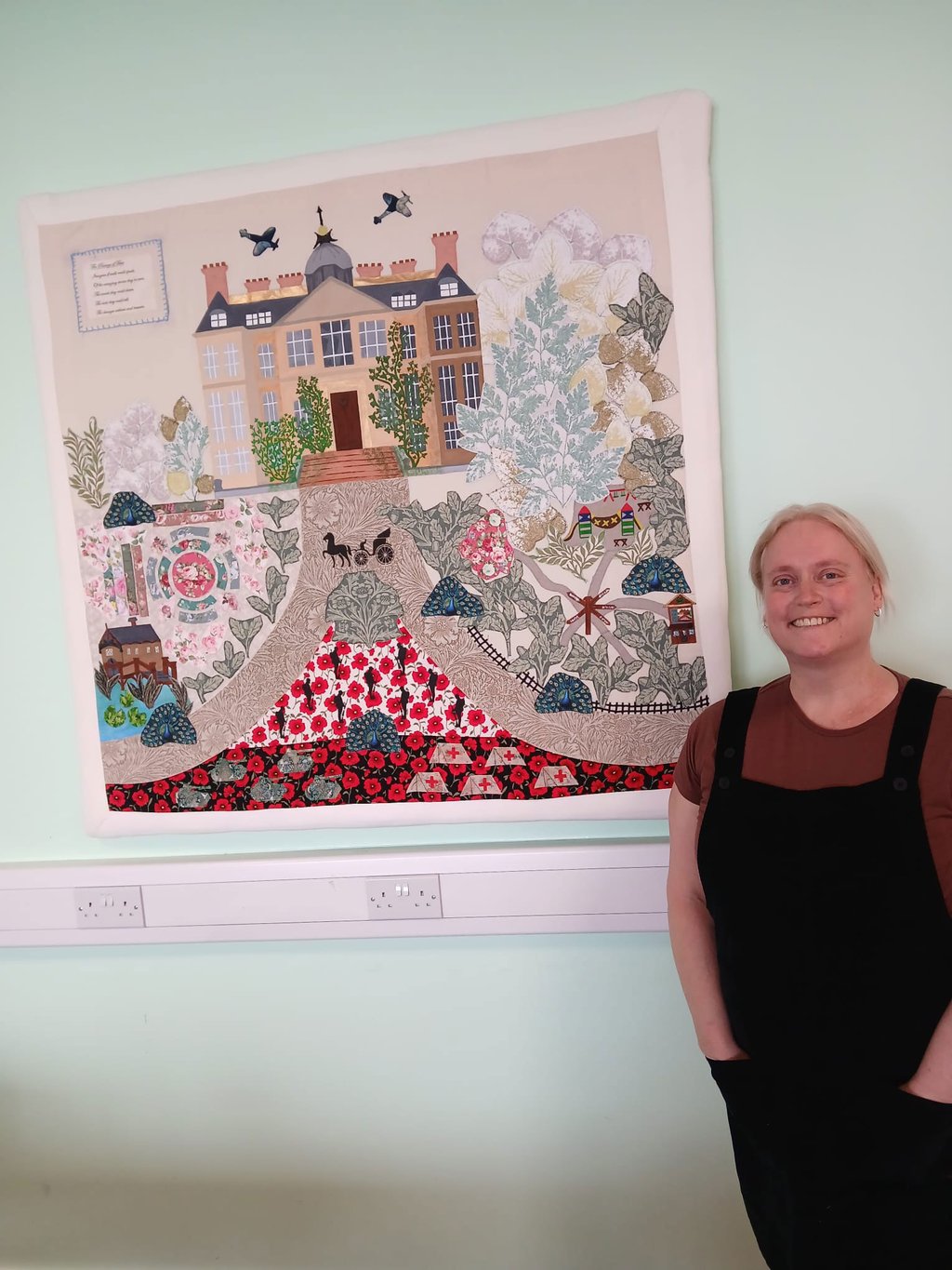 Vicky Roberts standing beside sewn artwork of Belton Estate.