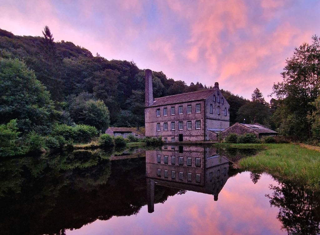 Gibson Mill reflected in the water beneath a pink sunset.