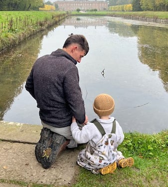 Father and son over reflective pond.