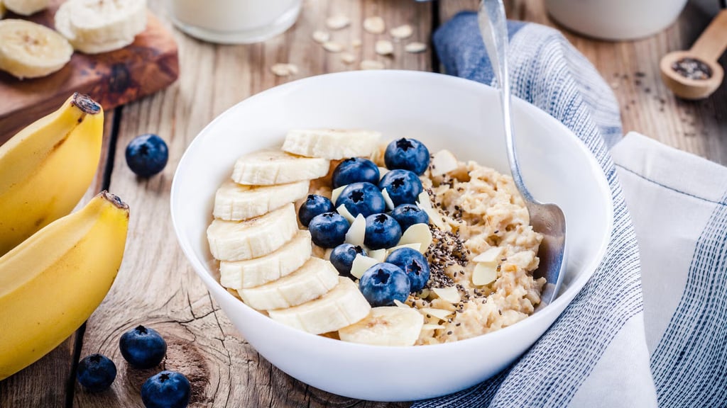 A bowl of cooked oatmeal and cut up fruit.