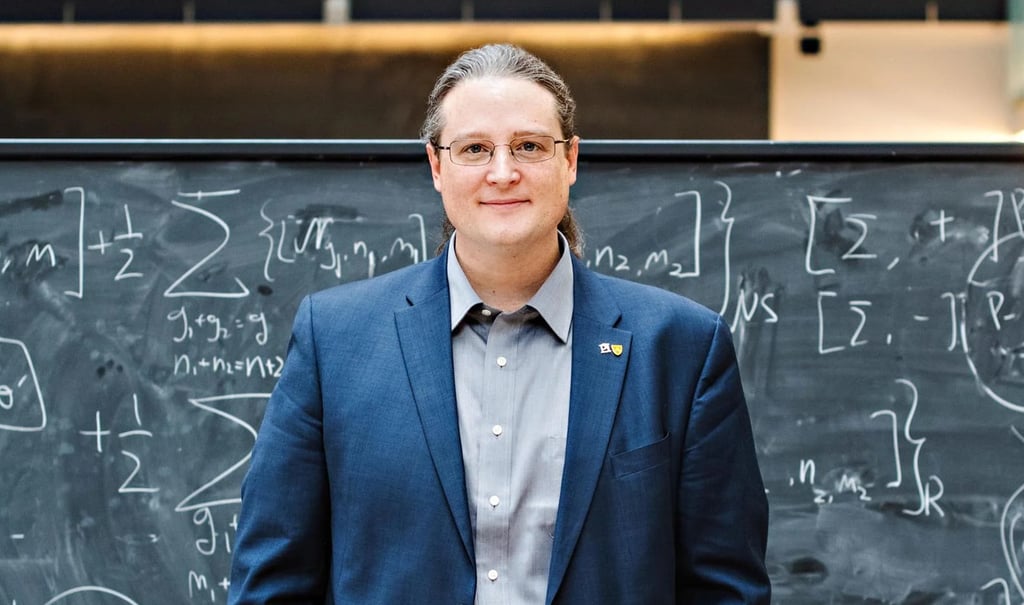 Dr. Avery Broderick standing in front of a black board.