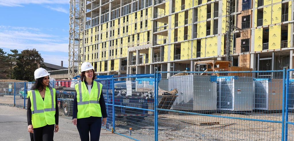 Leia Minaker and a student walk near a construction site while wearing safety equipment.